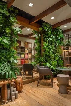 a room filled with lots of green plants and wooden flooring next to tables covered in potted plants