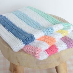 a wooden stool topped with a multicolored crocheted blanket