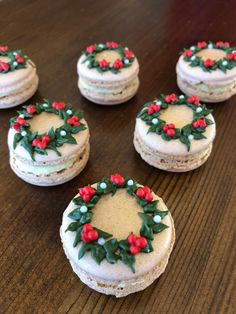 six decorated cookies sitting on top of a wooden table next to each other with holly decorations