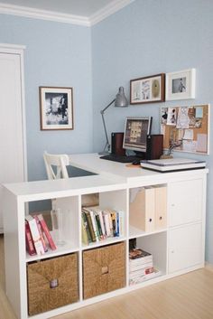 a white desk topped with lots of books next to a chair and pictures on the wall