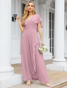 a woman in a long pink dress standing on steps with her hands in her pockets