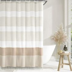 a bathroom with a bathtub, toilet and shower curtain in white and beige colors