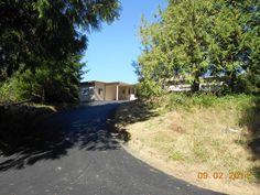 an empty road in the middle of a wooded area with two buildings on each side