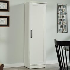 a tall white cabinet sitting next to a dining room table