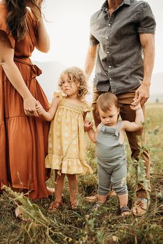 an adult and two children holding hands while standing in the grass