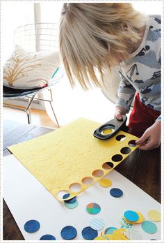 a child cutting out circles with scissors on top of a piece of paper that has been cut