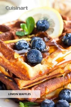 a stack of waffles topped with blueberries and lemon slices on a plate