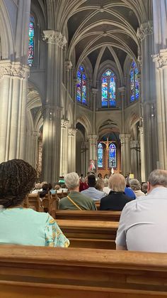 people are sitting in pews at the alter of a church with stained glass windows