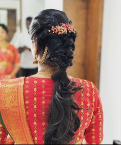 a woman with long hair in a red and gold sari is seen from the back