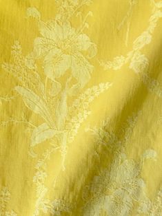 a yellow and white floral print fabric with an intricate flower design on the back side