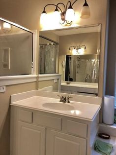 a bathroom with a sink, mirror and lights on the wall above it is shown