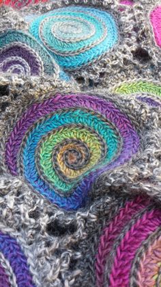 a multicolored crocheted blanket with circles and spirals on the edges