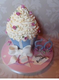 a cupcake decorated with white frosting and pink flowers on top of a pink plate