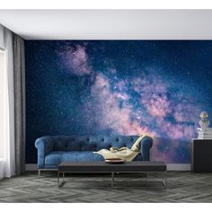 a living room with a blue couch and stars in the sky wall mural on it