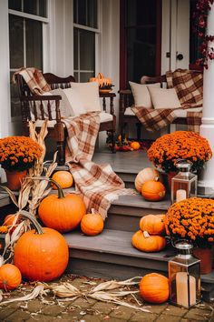 pumpkins and flowers on the front steps of a house