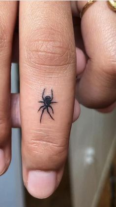 a person with a spider tattoo on their finger