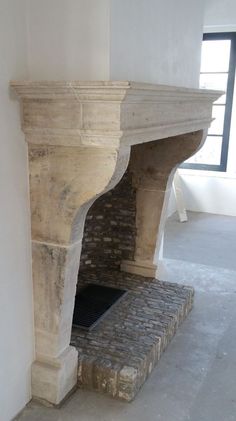 an old fireplace in the corner of a room with white walls and cement flooring