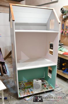 an unfinished dollhouse is shown in the process of being painted and put on display