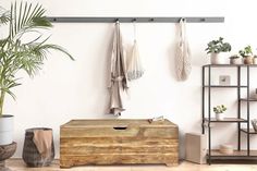 a living room filled with furniture and potted plants next to a wall mounted coat rack