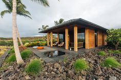 a small wooden house sitting on top of a lush green hillside next to a pool