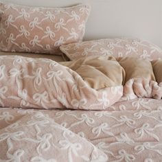 an unmade bed with pink and white comforter, pillows and blankets on it