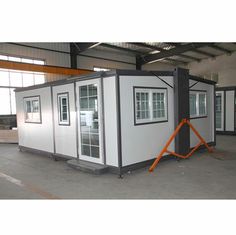 two white portable homes in a warehouse with windows on each side and one door open