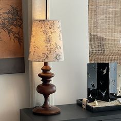 a lamp sitting on top of a wooden table next to a painting and other items