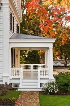 a white house with a covered porch in the fall