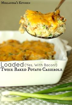 a spoon full of baked potato casserole on top of a white dish with green onions