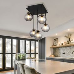 a modern kitchen with marble counter tops and stainless steel pendant lights hanging from the ceiling