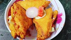 two pieces of fried food on a plate with onions, carrots and celery