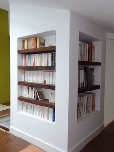 there are many books on the shelves in this room that is white and has wood flooring