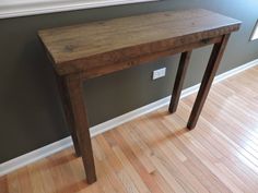 a wooden table sitting on top of a hard wood floor next to a white window