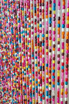 multicolored beads are hanging on the wall next to each other in an art project