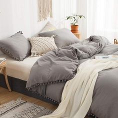 a bed with grey sheets and pillows in a room