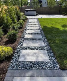 a walkway made out of stones in the middle of a yard with grass and bushes