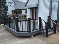 a deck with black iron railings and lights on the side walk leading up to a house