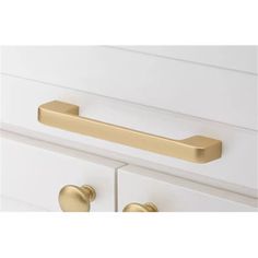 an image of a brass drawer handle on a white dresser with two drawers in the background