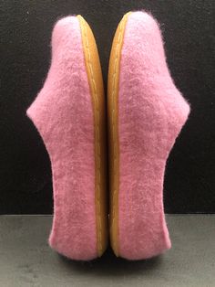 two pink slippers with yellow piping on them