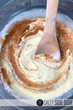 a wooden spatula in a glass bowl filled with brown and white food colorings