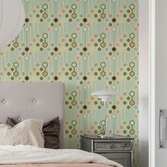 a bed sitting next to a green wallpaper with circles on it's headboard