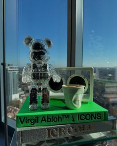 a teddy bear sitting on top of a stack of books next to a coffee cup