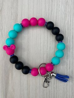 a bracelet with beads and tassels on top of a wooden table next to a keychain