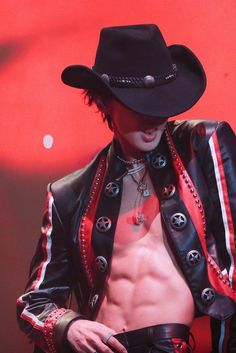 a shirtless man wearing a black cowboy hat and leather jacket with red stripes around his chest