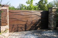 a gate that is next to a brick wall and some trees in the back ground