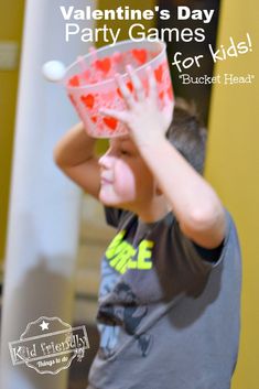 a young boy holding up a plastic cup filled with watermelon and text valentine's day party games for kids bucket head