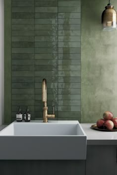 a white sink sitting under a faucet next to a green tiled kitchen wall