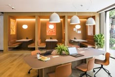 an office with orange chairs and desks in front of large glass doors that look out onto the street