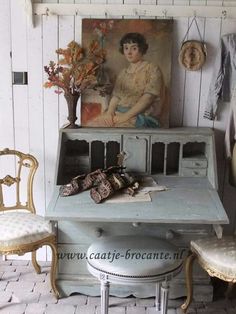 an old desk with a painting on the wall