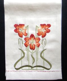 a white towel with red flowers on the front and green stems in the middle, sitting on a black surface